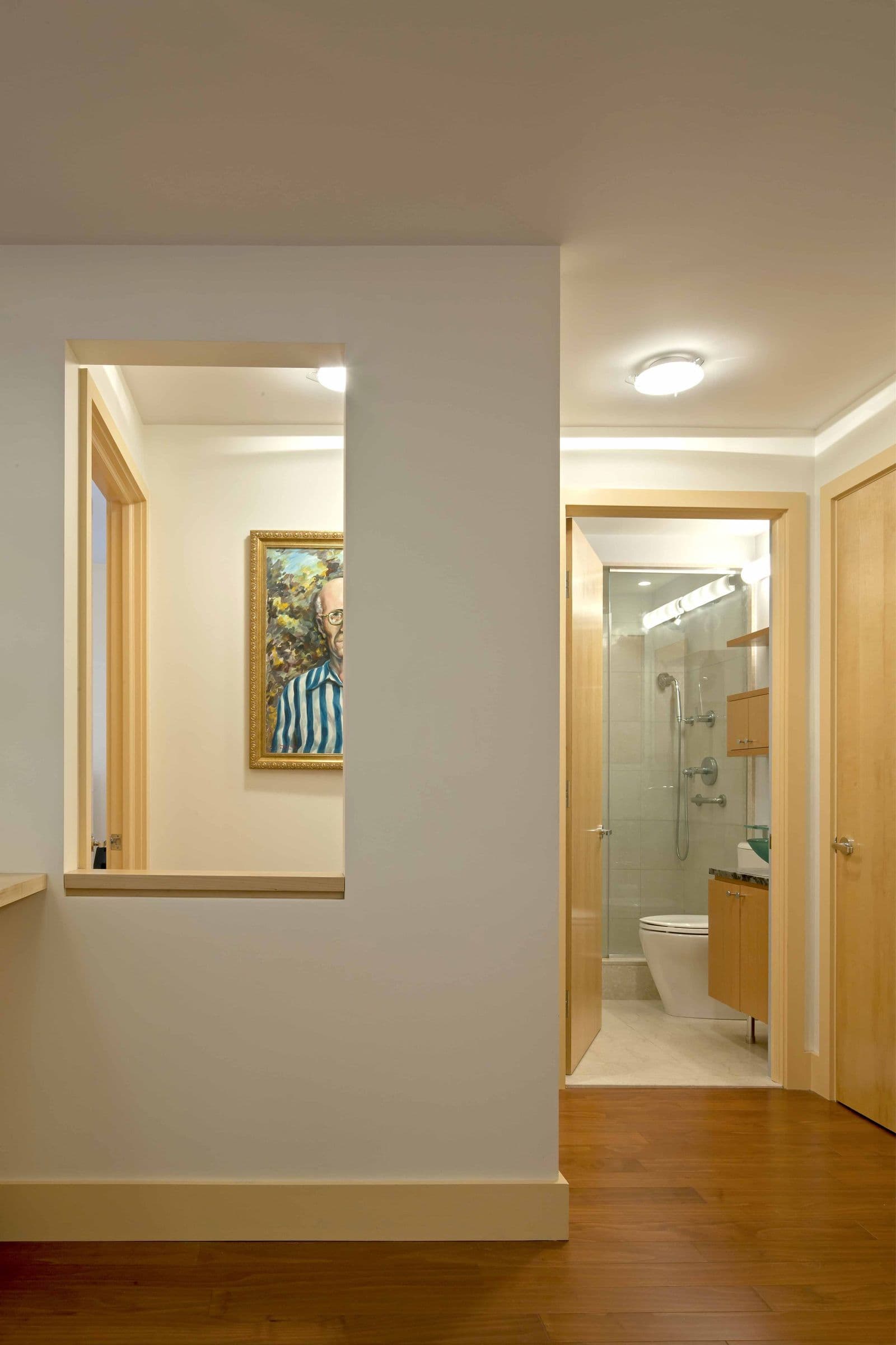 A hallway in the Baxter Residence with a framed interior opening carrying daylight through the apartment