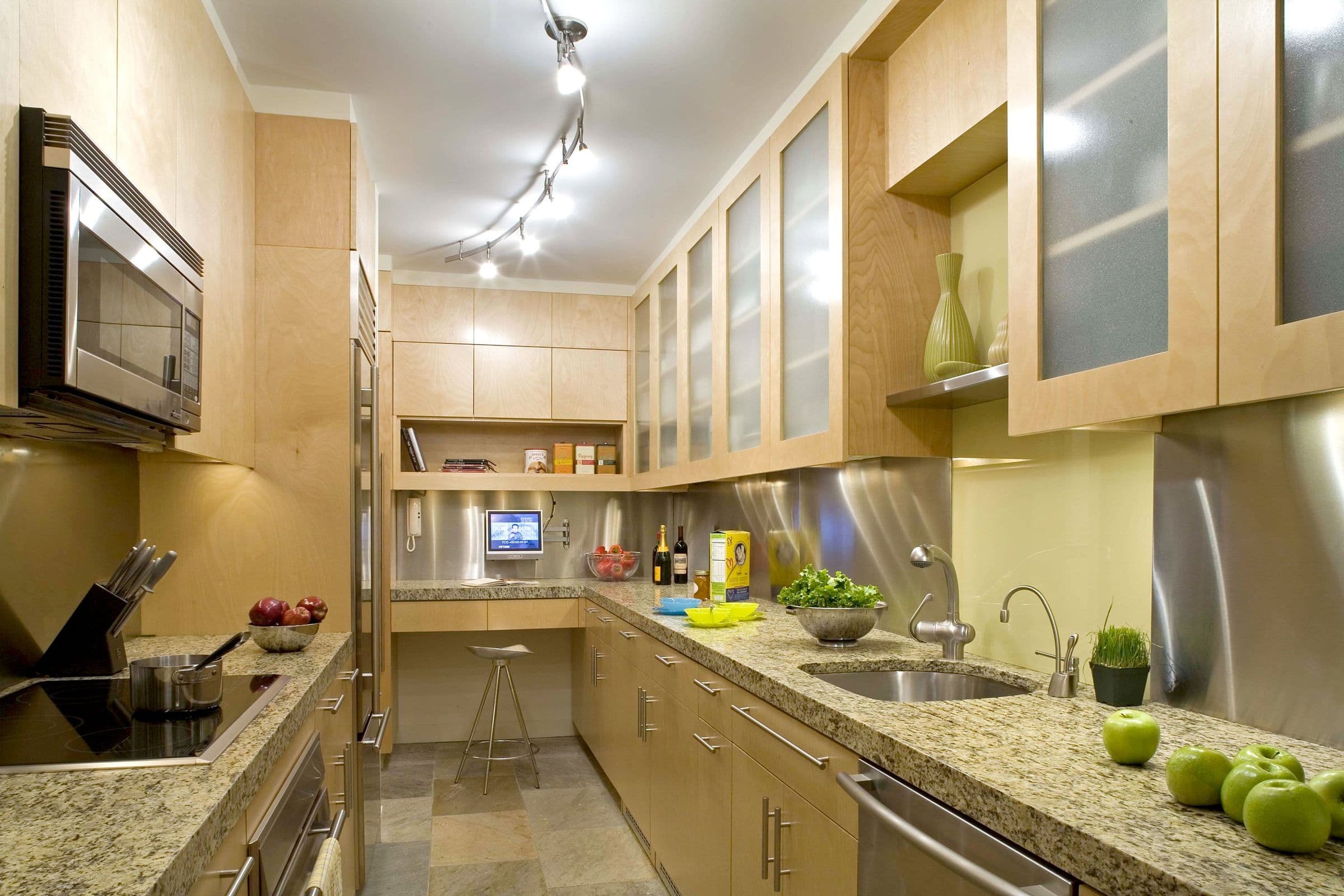 Maple cabinetry, granite counters and a stainless steel backsplash along the Shaw Residence kitchen work wall