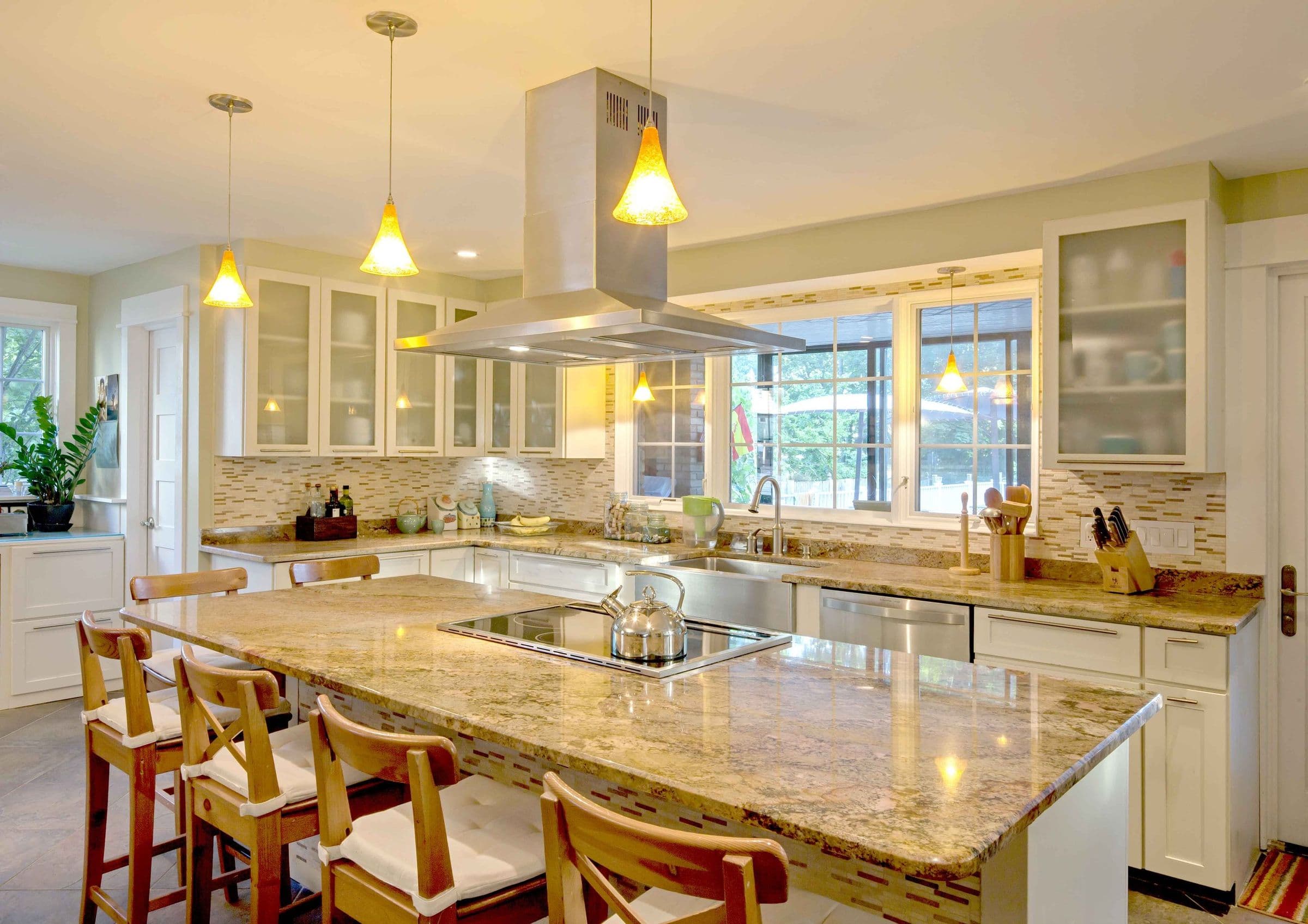 The Brión Residence kitchen island with granite counters, pendant lighting and a stainless hood