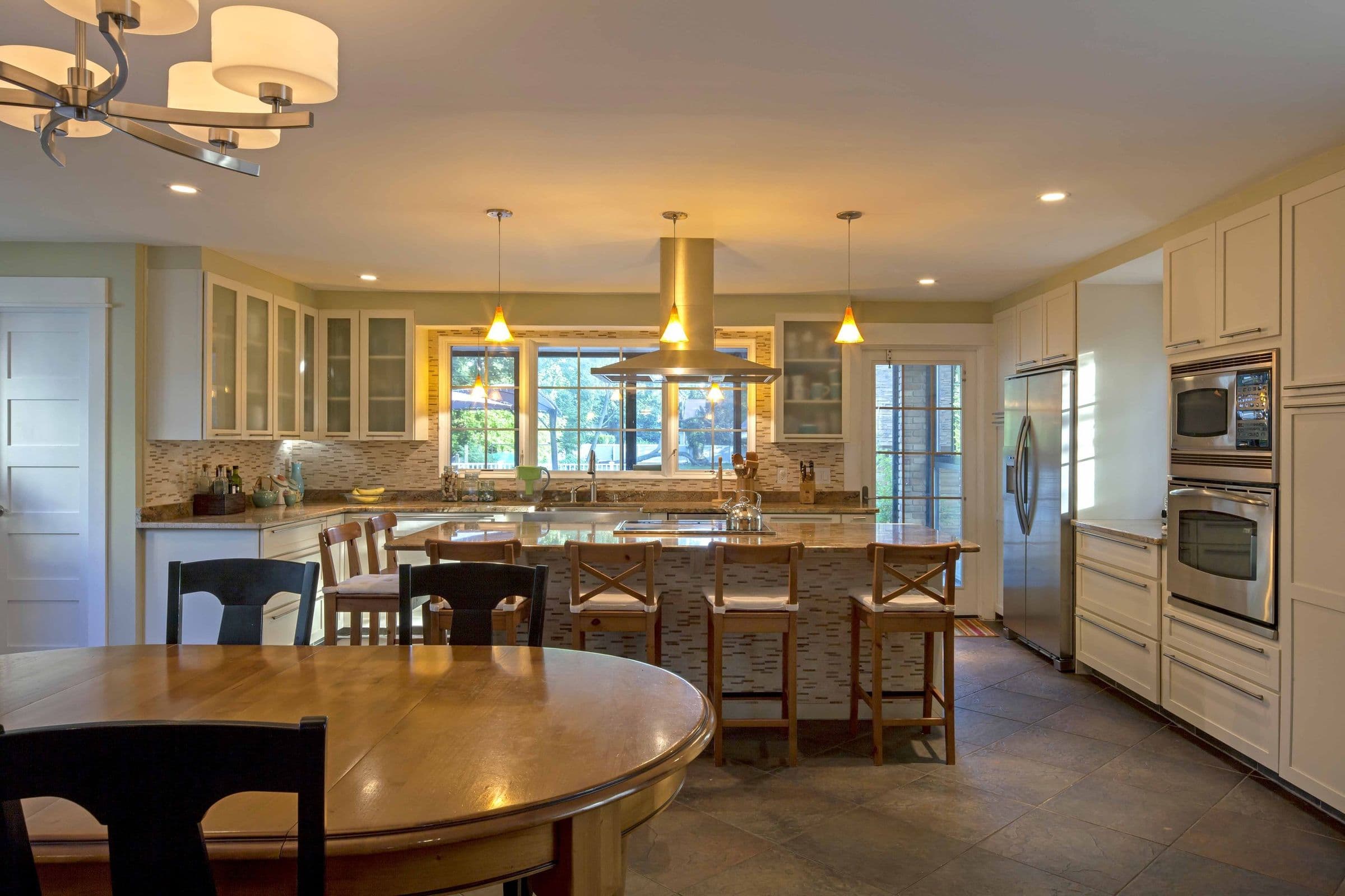 The Brión Residence kitchen after the expansion, an island with seating and a dining table by the windows